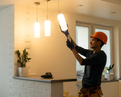 Electrician installs lamp lighting and spot loft style.