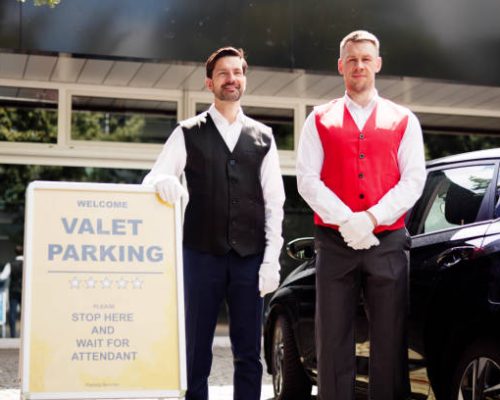 Skilled Valet Providing Exceptional Service Under Hotel Sign, Representing Top-notch Hospitality in City's Thriving Business Industry.