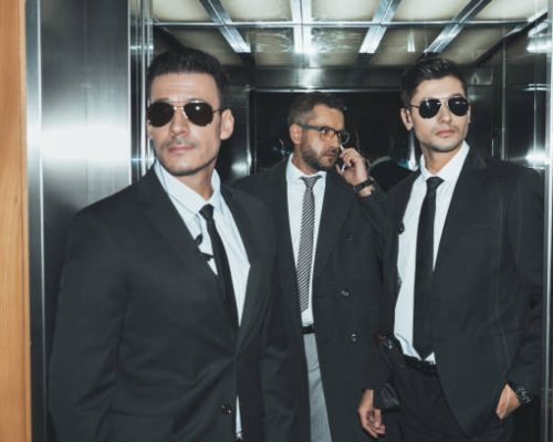 bodyguards reviewing territory when businessman talking by smartphone in elevator